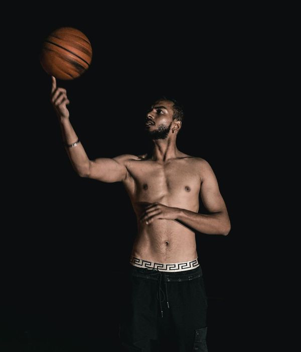Man in a focused pose performing a strength exercise in a dark room.