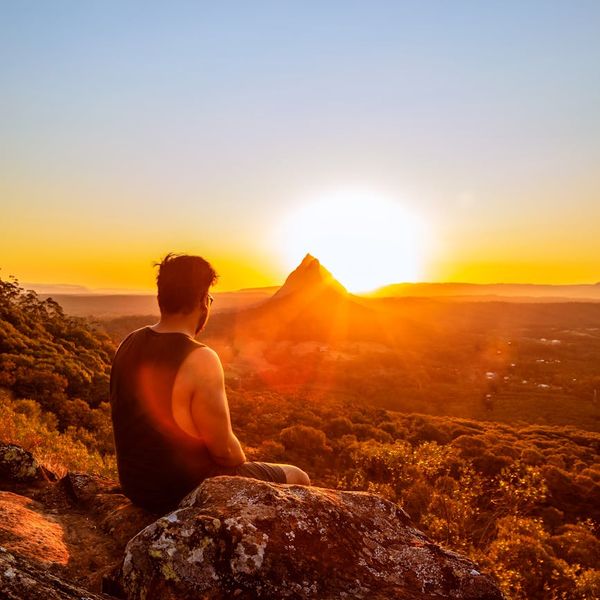 Silhouette of a man meditating at sunrise with a mountain view.